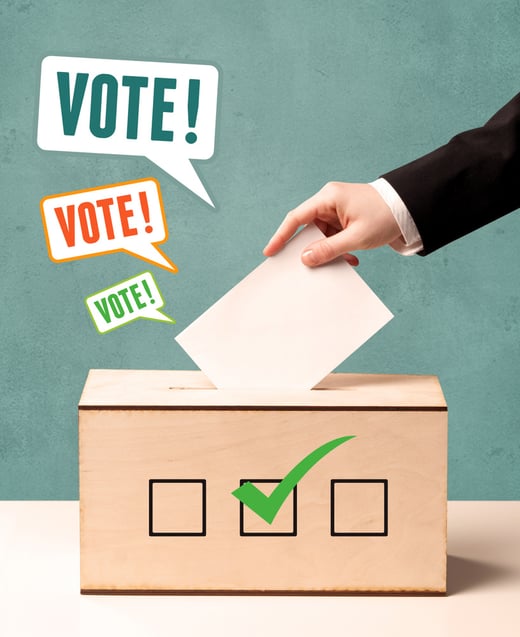 A hand placing a voting slip into a ballot box-1